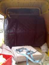 An upright piano strapped up for transport in the van. An upright piano strapped up for transport in the van.